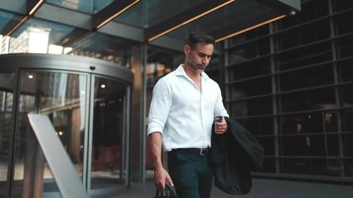 Mature businessman leaves the office in the financial district in the city