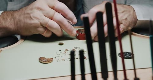A professional watchmaker carefully disassembling a watch for repair and cleaning - close up