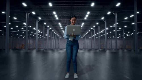 Asia Female Professional Worker Use A Laptop in Empty Warehouse