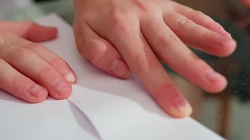 Closeup Hand Folding and Creating Paper Craft on Table with Precision