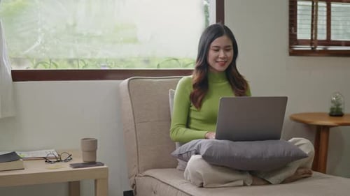 Woman wears green sweater working studying and liniving at home.