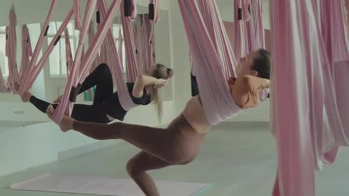 Women participating in aerial yoga class in a modern studio