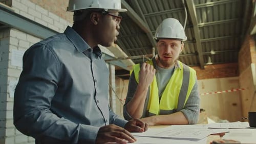 Engineer and Foreman Working on Building Plans at Construction Site