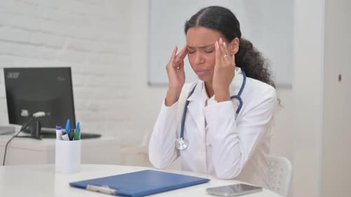 Tired African Female Doctor with Headache in Clinic