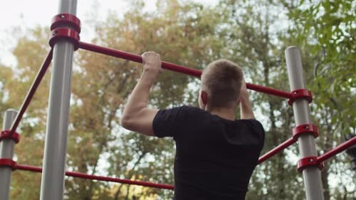 Athletic Man Pulls Up on the Horizontal Bar