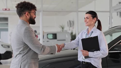 Car Dealership Saleswoman Shaking Hands with Customer
