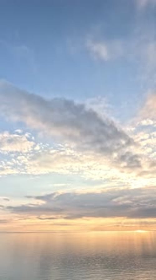 Timelapse : cumulus moelleux se déplaçant dans un ciel doré brillant au coucher du soleil au-dessus de la mer, nature aérienne abstraite
