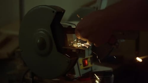 Unrecognized carpenter sharpening iron tool with lathe machine in carpentry workshop
