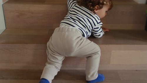 Infant Cautiously Crawls Up Wooden Indoor Stairs