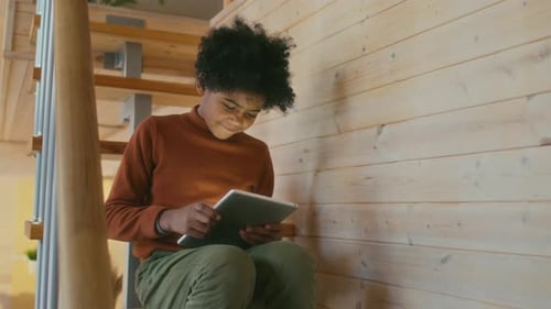 Child Sitting on Stairs Using a Tablet