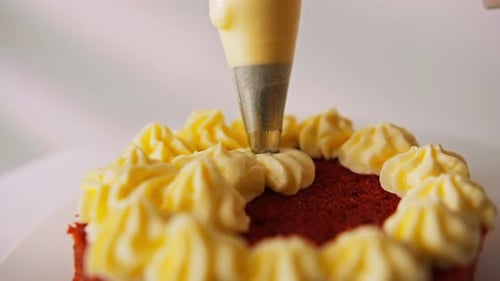 Red Cake Being Decorated With Yellow Icing