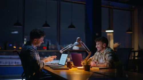 Two Young Adults Working at Night in Office