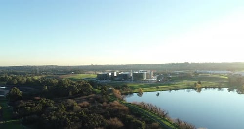 Arrow shot drone aerial perspective moving toward modern business park with car arriving at car park