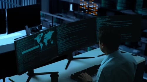 Side View Of Asian Man Using Computer To Write Code With Multiple Screens In office