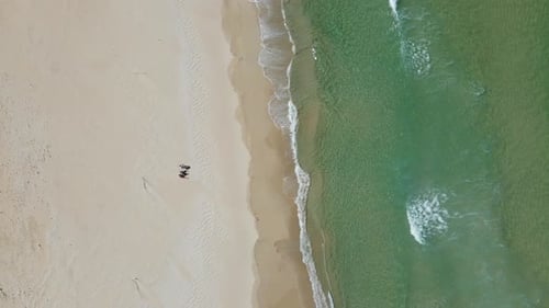 three people sitting in white sand and enjoying day on the beach in front of a crystal clear ocean w