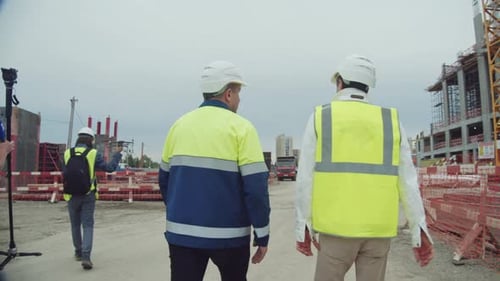 Engineers with Helmets and Filming Crew at Construction Site