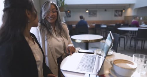Businesswomen Working at Laptop at Cafe Table 10 Seconds or Greater