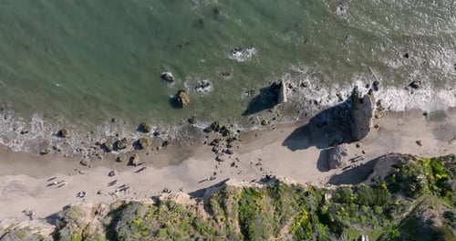 Aerial top view of ocean blue waves break on a beach.