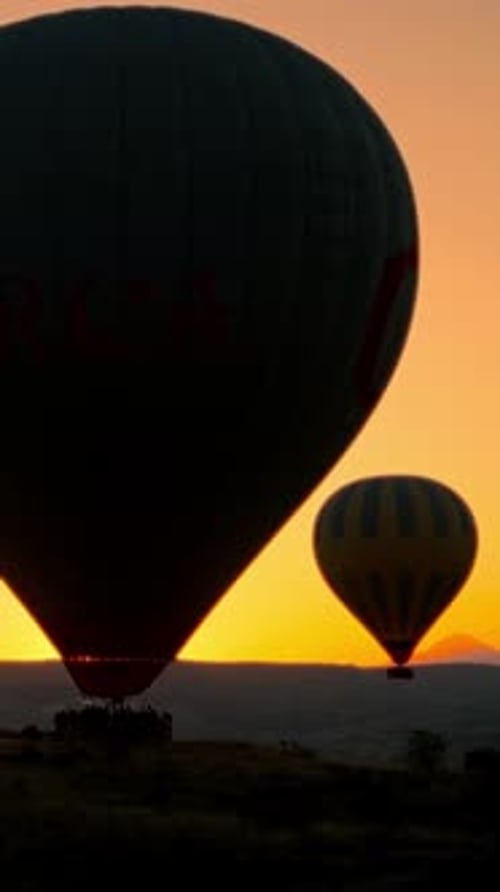 Hot air balloon flight lift off silhouetted in dawn Turkish orange sky