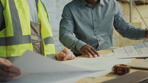 Construction Workers Reviewing Building Plans at Workplace