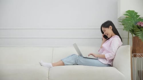 Woman Using Laptop and Phone on Couch