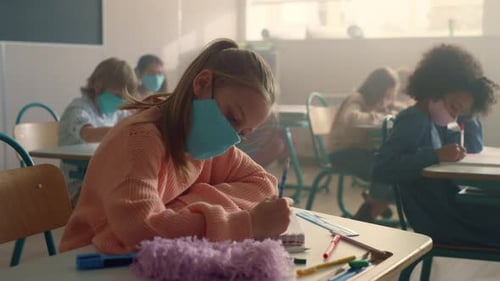 Children Wearing Masks Write in Classroom During School