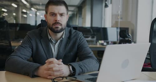Serious Man at Desk With Laptop in Office