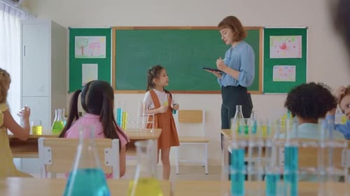 Adorable student learn with teacher in classroom at elementary school.