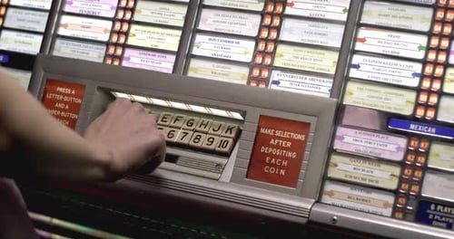 Selecting a song on a vintage 1950s jukebox keypad, retro close-up detail.