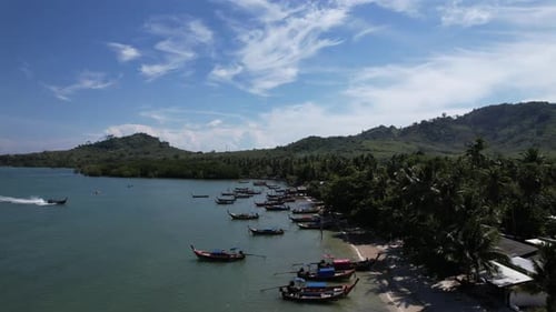 Footage of a lot of long-tailed boats float on the sea outside the white beach.