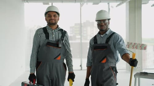 Zwei verschiedene Bauarbeiter in Uniform und Helmen auf der Baustelle