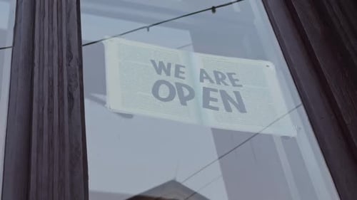 A Sign on a Storefront Window Welcomes Customers and Informs Them That the Store is Open