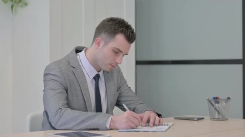 Young Businessman Working on Documents in Office