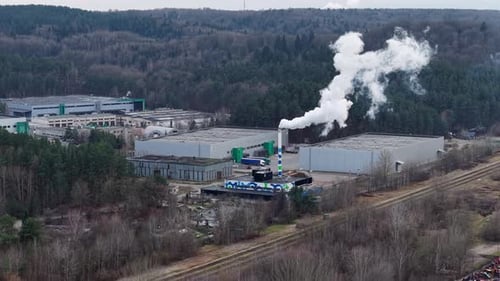 Aerial View of Factory with Smoke Near Forest