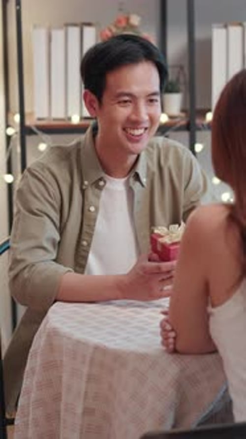 Man Giving Present to Woman at Table Indoors