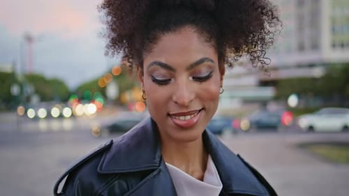 Chica urbana relajándose en la calle vistiendo una chaqueta moderna, retrato de cerca, modelo africana