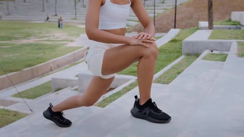 Young fitness woman in sportswear exercising in city park