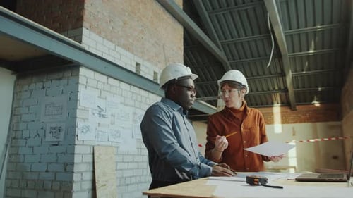 Male and Female Architects Discussing Floor Plan and Building Interior on Site