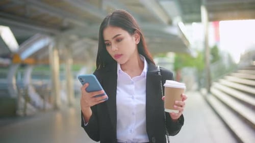 Fashionable Woman Using Phone with Coffee in City