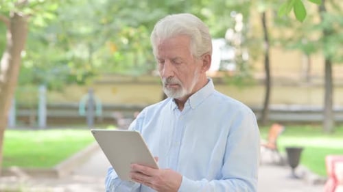Senior Man Uses Tablet Outdoors