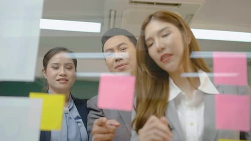 Team Brainstorming Using Sticky Notes on Glass Wall