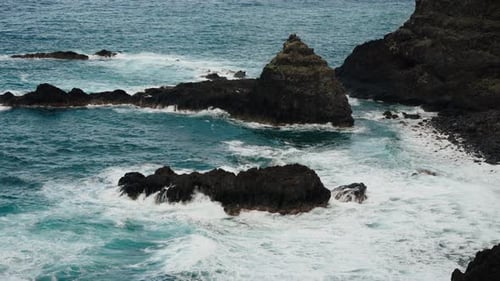 Waves Crashing Against Dark Rocks on Ocean Coast
