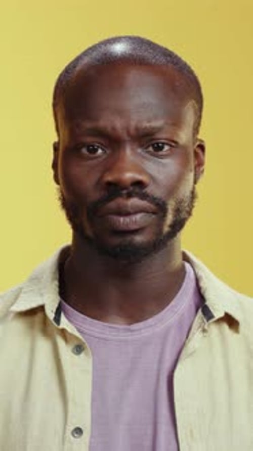 Un portrait captivant d'un homme confiant posé sur un fond jaune vif
