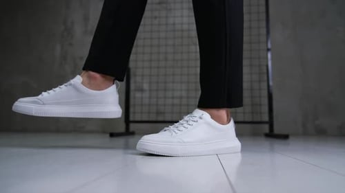 Stylish snow-white sport shoes with laces on a model.