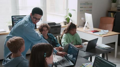 Teacher Interacting with Group of her Students During IT Class in School
