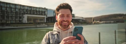 Smiling Man Using Phone in Urban Setting