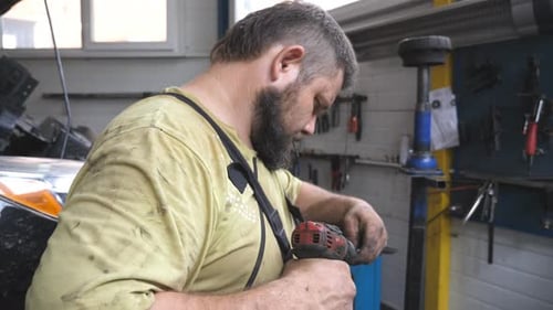 Man Using Electric Drill in Auto Repair Garage
