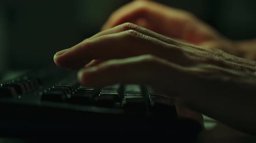 Die Tasten einer Computertastatur werden vorsichtig von den Händen eines arbeitenden Mannes gedrückt
