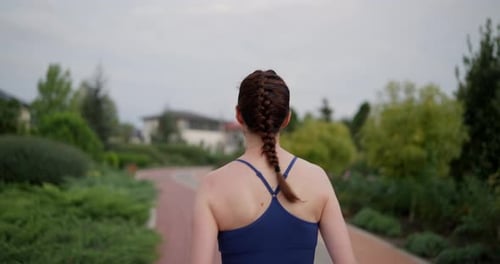 Rear View of a Happy Brunette Girl in Blue Sportswear Running During Her Morning Jog in the Park in