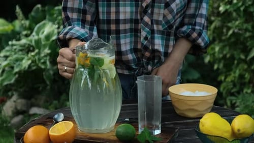 Summer Drink Pouring Homemade Lemonade Into Glass in Backyard Garden